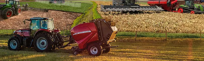 A Massey Ferguson tractor is towing another piece of Massey Ferguson equipment in an agricultural field.